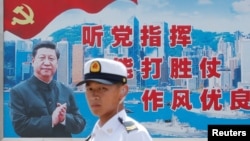 資料照：一名中國解放軍海軍士兵在香港的海軍基地站在有著中國領導人習近平畫像的宣傳標語前。（2016年7月8日）