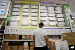 A man looks at a a wall displaying air conditioning models on sale at department store, in Rome, July 25, 2023.