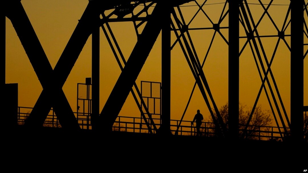 A man walks across the Puente Negro Ferrocarril rail bridge that connects Mexico and the US, Jan. 3, 2024, in Eagle Pass, Texas.
