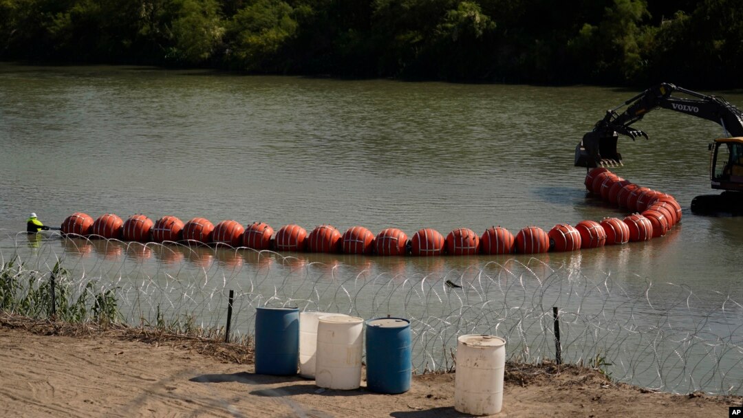 FILE - Workers deploy a string of large buoys to be used as a border barrier at the center of the Rio Grande near Eagle Pass, Texas, July 11, 2023. The floating barrierwas deployed in an effort to block migrants from entering Texas from Mexico. 