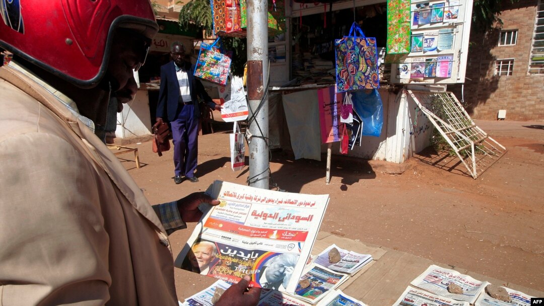 FILE - A man reads newspaper headlines in Sudan's capital, Khartoum, Nov. 8, 2020. 