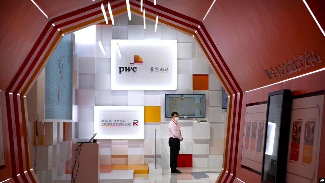 FILE - A staff member wearing a face mask stands at a booth for the consulting firm PricewaterhouseCoopers (PwC) at the China International Fair for Trade in Services (CIFTIS) in Beijing, Sept. 5, 2020.