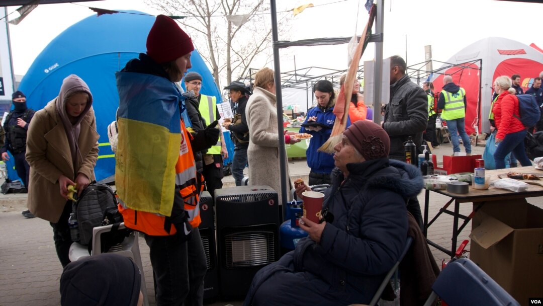 Already dazed refugees emerge from Ukraine into a winding path of tents and small marquees and they run a gauntlet of charity and hospitality, which at first adds to their disorientation, but as they relax it prompts smiles. (Jamie Dettmer/VOA)