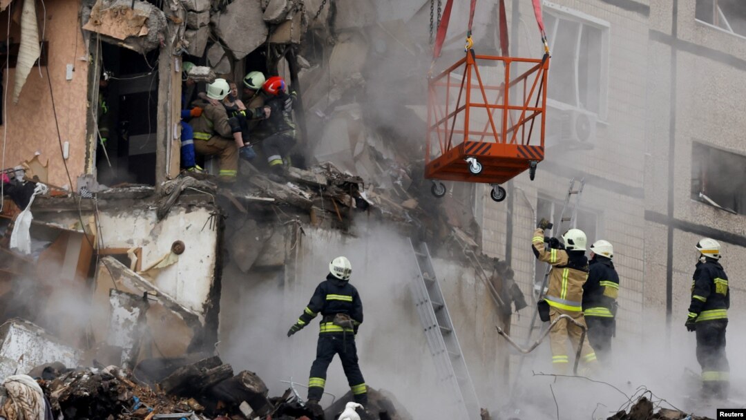 Emergency personnel evacuate a woman at the site where an apartment block was heavily damaged by a Russian missile strike in Dnipro, Ukraine, Jan. 15, 2023. 