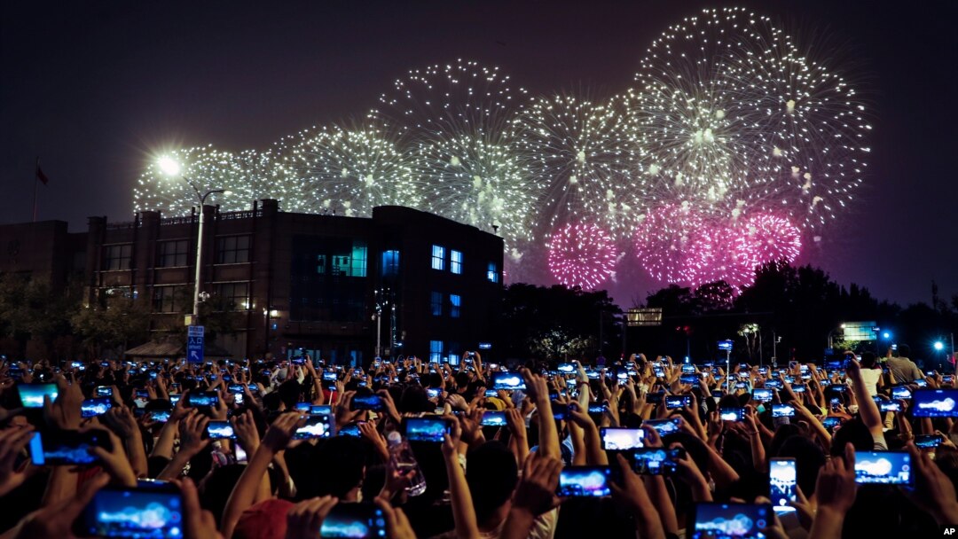 FILE - People use smartphones to film fireworks exploding at Tiananmen Square in Beijing on Oct. 1, 2019, as part of a gala evening commemorating the 70th anniversary of the founding of Communist China.