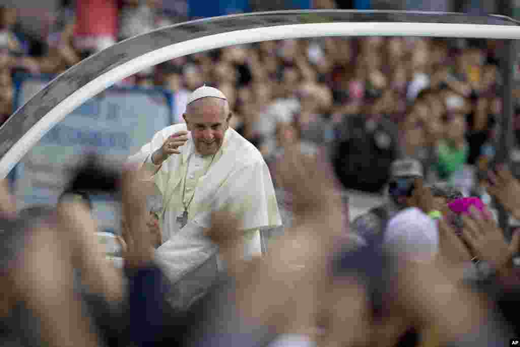 Pope Francis greets people from his popemobile in the Gloria neighborhood on his way to the archbishops's palace in Rio de Janeiro, Brazil.