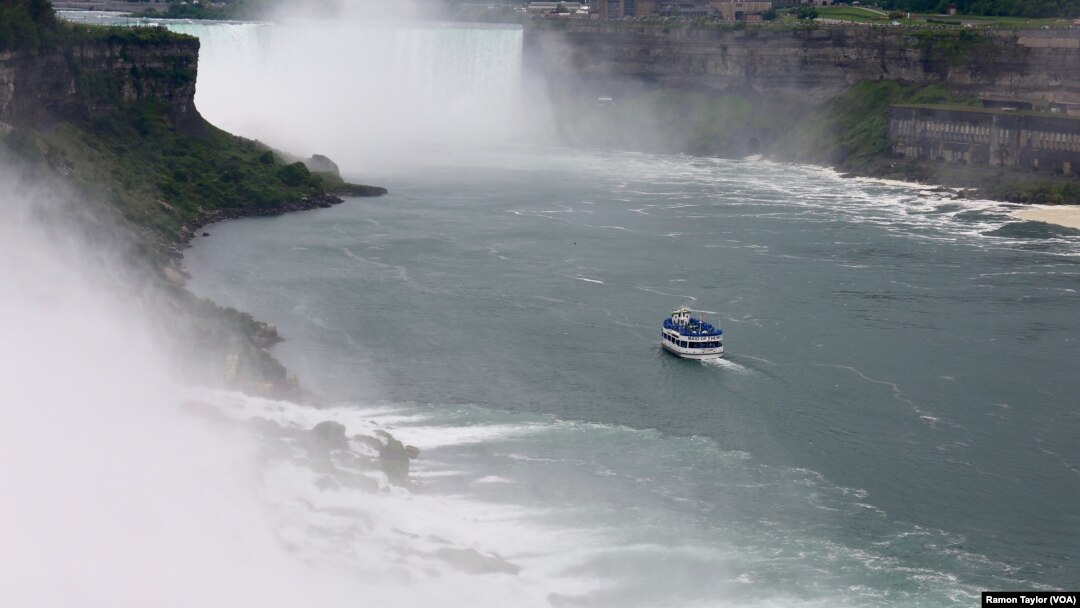 A ‘Maid of the Mist’ vessel sails past the American and Bridal Veil Falls, toward Horseshoe Falls, where poncho-suited tourists are often soaked by a thick mist. (R. Taylor/VOA)