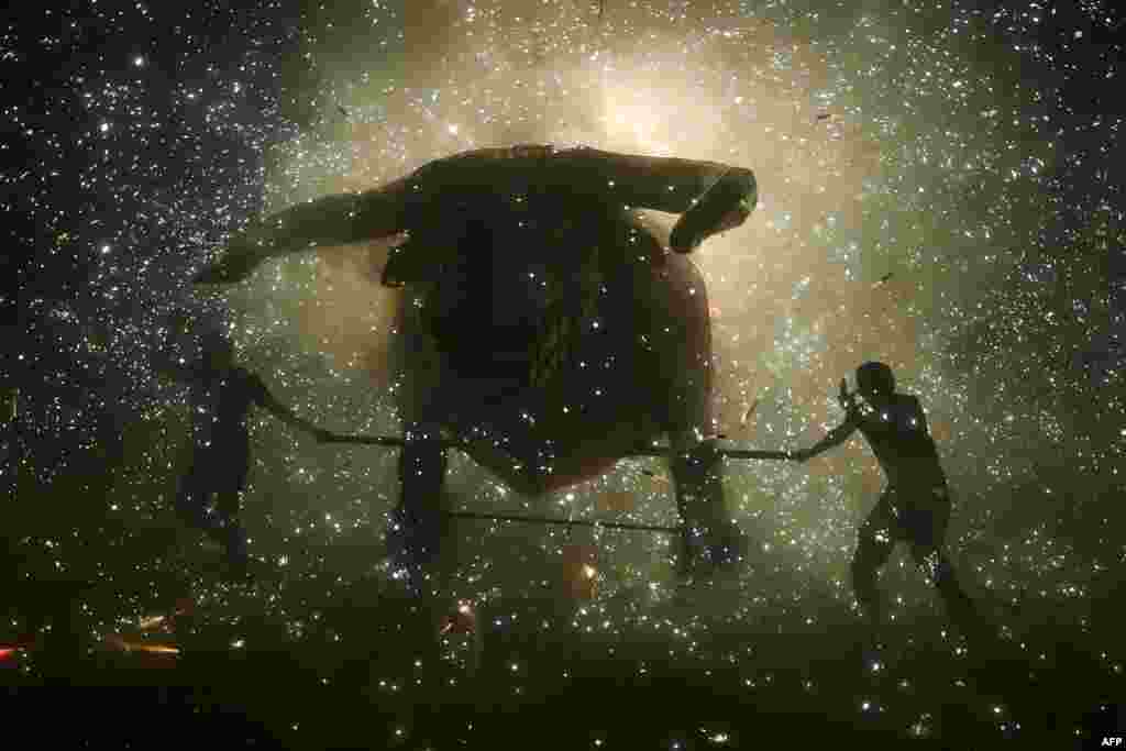 People stand beneath the sparks of fireworks beside the traditional &quot;torito&quot; (little bull) made of paper and wood&nbsp; during celebrations of San Juan de Dios in Tultepec, on the outskirts of Mexico City, March 8, 2022.