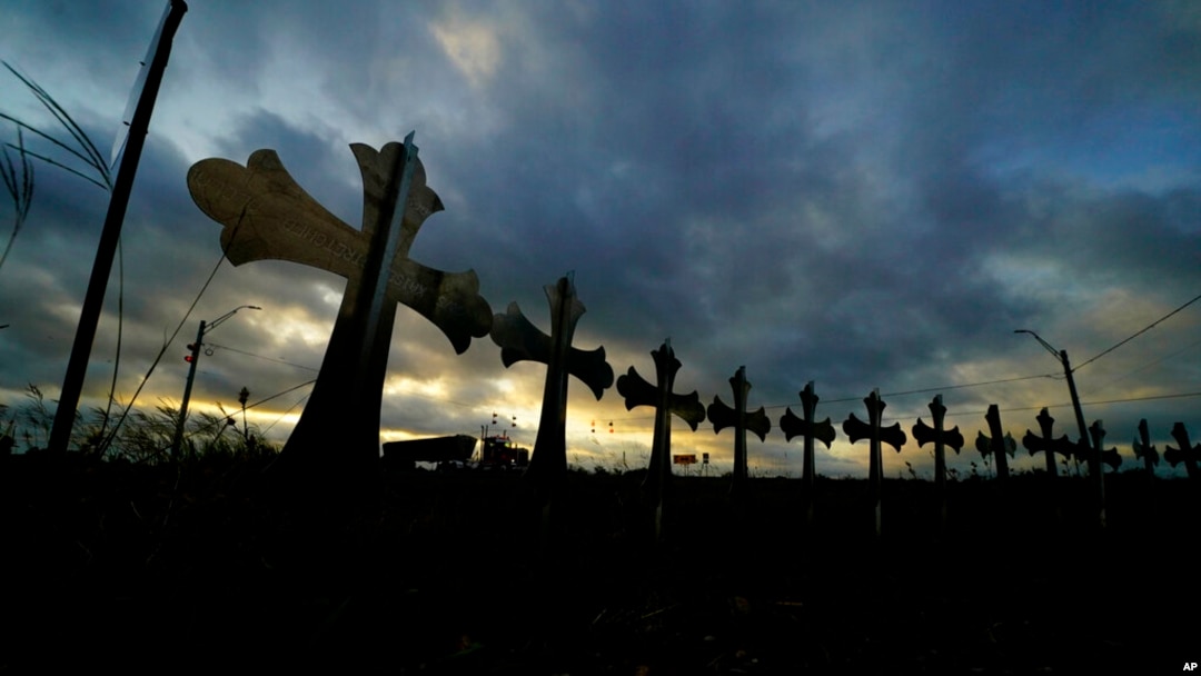 ARCHIVO - Un camión pasa frente a cruces colocados a lo largo de la carretera en honor a las víctimas muertas en el reciente tiroteo en la escuela primaria Robb, en Uvalde, Texas, el 6 de junio de 2022.