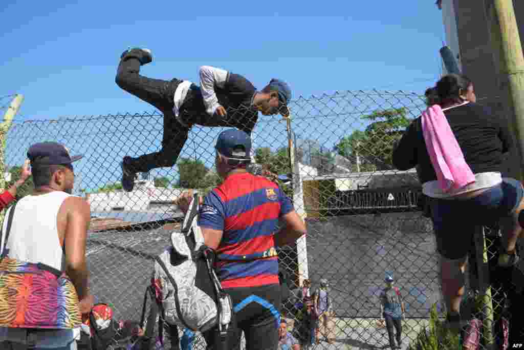 Salvadorean migrants climb and jump over a fence to get to the Guatemala-Mexico international border bridge in Ciudad Tecun Uman, Guatemala.