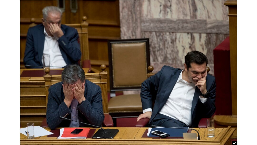FILE - Greek Finance Minister Euclid Tsakalotos, left, and Greece's Prime Minister Alexis Tsipras, right, react during a parliamentary session to vote on more austerity measures as part of an agreement with international bailout creditors, in Athens, May 18, 2017.