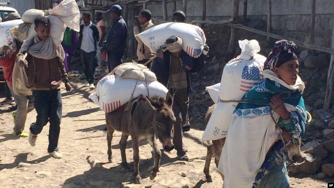 ሰዎች ከእስታየሽ ተብሎ በሚታወቀው የምግብ ማእከል በደንከና ቀበሌ መከት ወረዳ የምግብ እርዳታ ተቀብለው ወደየመኖርያቸው በሚጉጓዙበት ጊዜ የተነሳ ፎቶ[አሶሽየትድ ፕረስ/AP]
