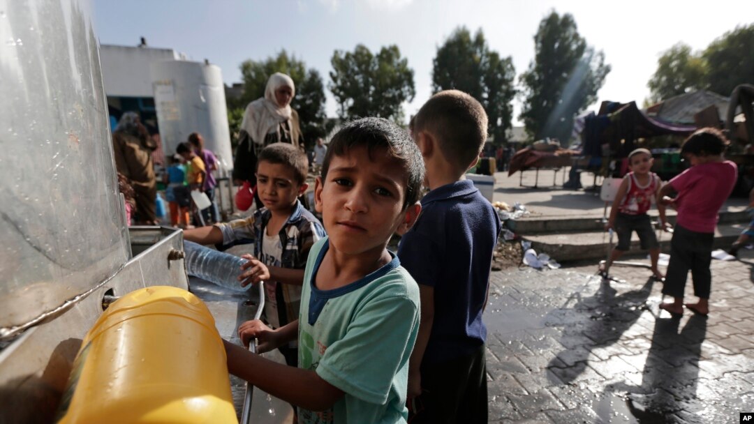 Displaced Palestinian children collect water at the Abu Hussein U.N. school in Jebaliya refugee camp, northern Gaza Strip, on July 30, 2014. It had been hit by artillery shells earlier in the day. 