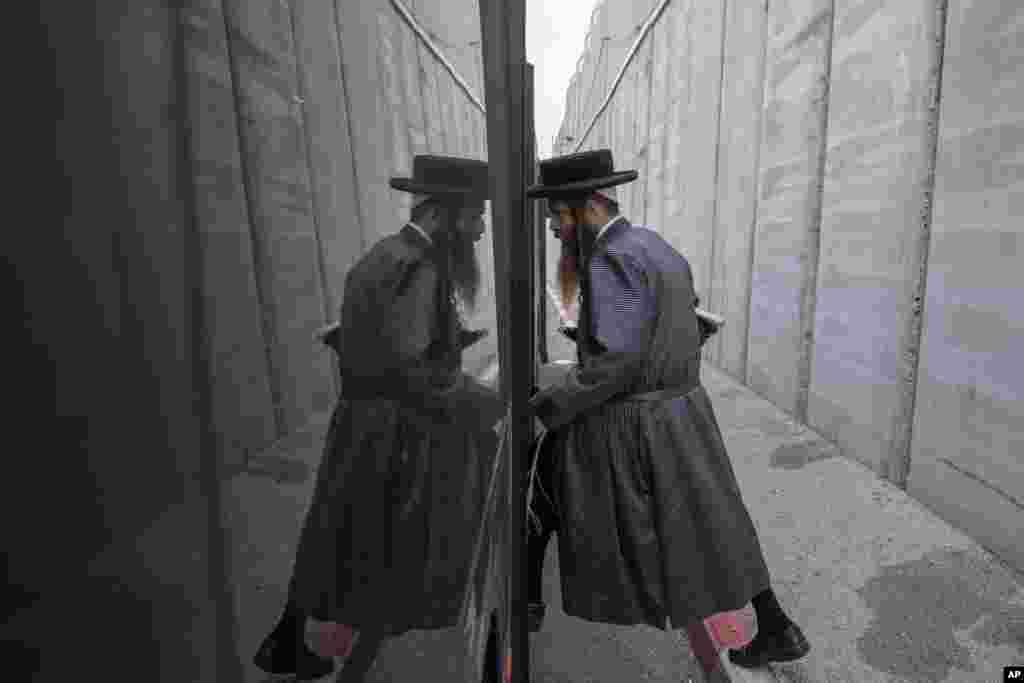 An Ultra Orthodox Jewish man gets on a bus near by the concrete barrier built by Israel to secure the Rachel's Tomb Judaism's third holiest shrine, during an annual mass prayer that drew tens of thousands of worshippers to commemorate the Jewish Matriarch Rachel, in the west bank town of Bethlehem.