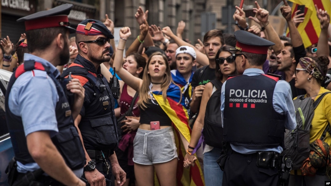 Catalan regional Mossos d'Esquadra police officers stand between protesters and the national police headquarters during a one-day strike in Barcelona, Oct. 3, 2017. 