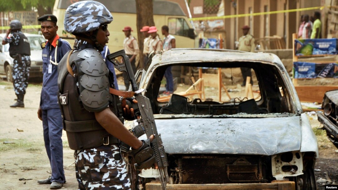 A policeman stands near damaged vehicles after a suicide car bomber killed five people on a street of popular bars and restaurants in Sabon Gari, Kano, Nigeria, May 19, 2014.