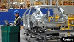 在重慶市福特汽車製造廠的生產線上，一名員工在旁使用筆記本電腦。(路透社資料照)