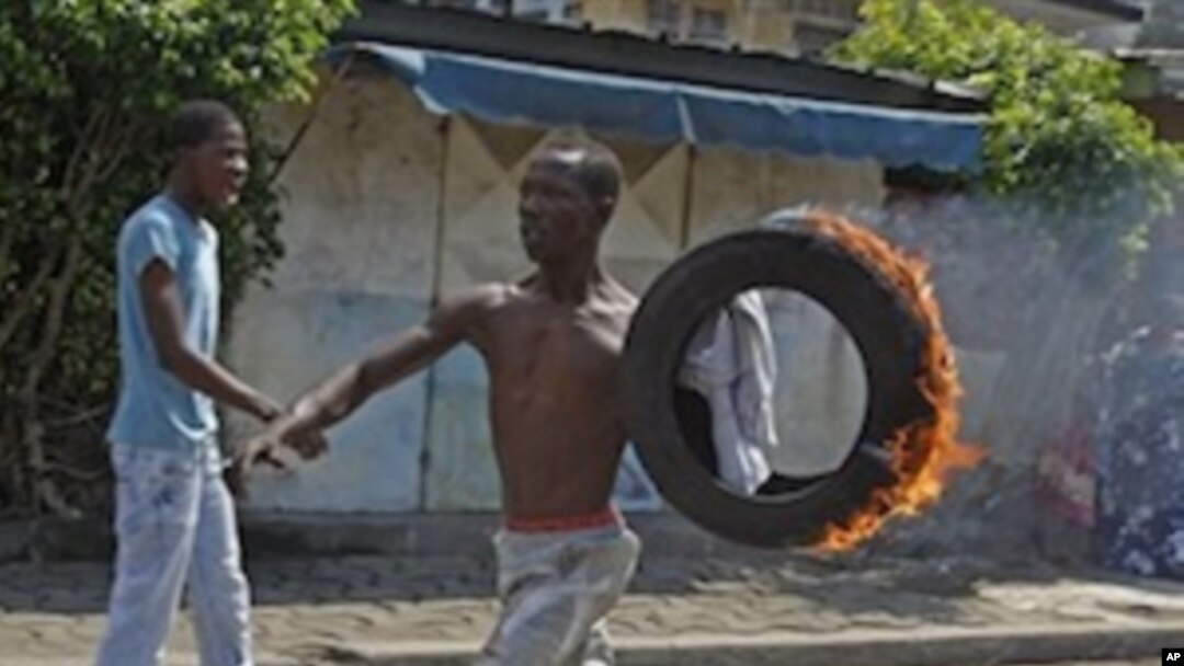 A supporter of Ivory Coast opposition leader Alassane Ouattara carry a burning tire during a protest in the city of Abidjan, Ivory Coast, Saturday, Dec. 4, 2010.