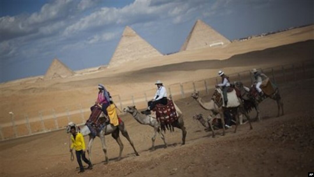 Tourists ride camels near the pyramids, in Giza, Egypt, January 31, 2011. The pyramids are closed to tourists.