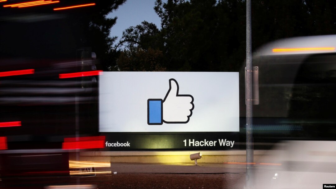 FILE - The entrance sign to Facebook headquarters is seen through two moving buses in Menlo Park, California, Oct. 10, 2018.