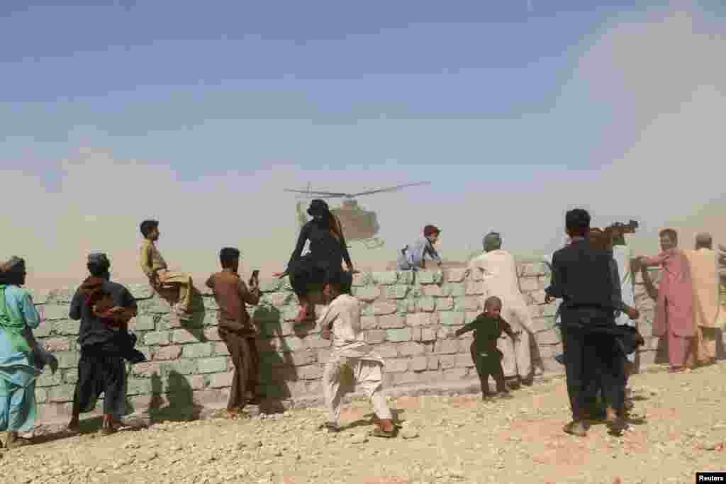 Residents gather as a rescue helicopter with medical supplies lands following an earthquake in Harnai, Balochistan, Pakistan.