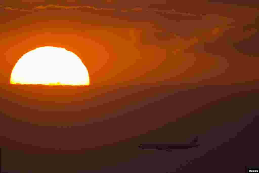 A passenger jet flies past the setting sun in Shanghai, China. 