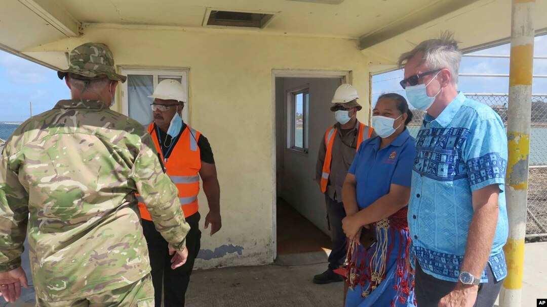 New Zealand High Commissioner Peter Lund, right, and military personnel stand on a dock in Nuku'alofa, Tonga, Jan. 21, 2022 after receiving a New Zealand ship that brought provisions.