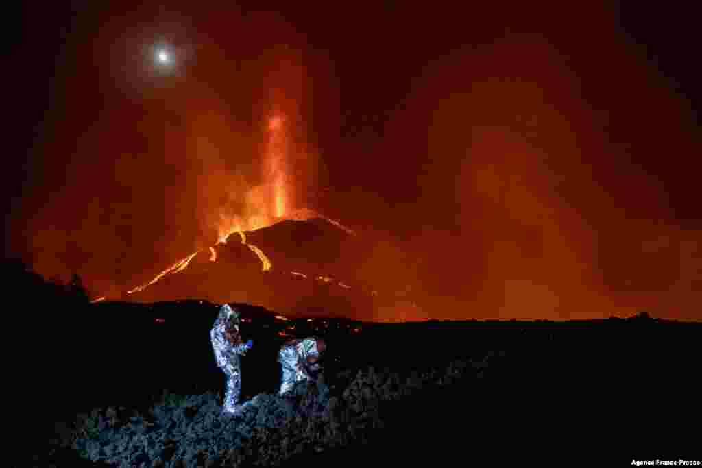 In this handout photograph taken and released by the Spanish Military Emergency Unit (UME) on Oct. 16, 2021, members of the GIETMA (Technological and Environmental Emergencies Intervention Group) of the UME monitor the evolution of a new lava flow, following the eruption of the Cumbre Vieja volcano, on the Canary island of La Palma.