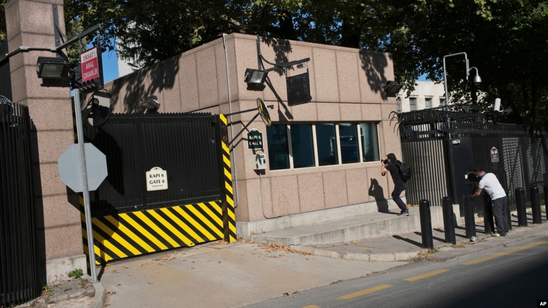 Periodistas toman fotos del daño a una puerta del puesto de seguridad por disparos efectuados desde un automóvil en movimiento frente a la embajada de EE.UU. en Ankara, Turquía, el lunes, 20 de agosto de 2018.