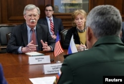 Russia's Defense Minister Sergei Shoigu, back to camera, meets with U.S. national security adviser John Bolton in Moscow, Oct. 23, 2018.