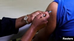 Mfanyakazi wa afya akitoa chanjo ya Pfizer kwa mtu mmoja mjini Johannesburg, Afrika Kusini Desemba 9, 2021.