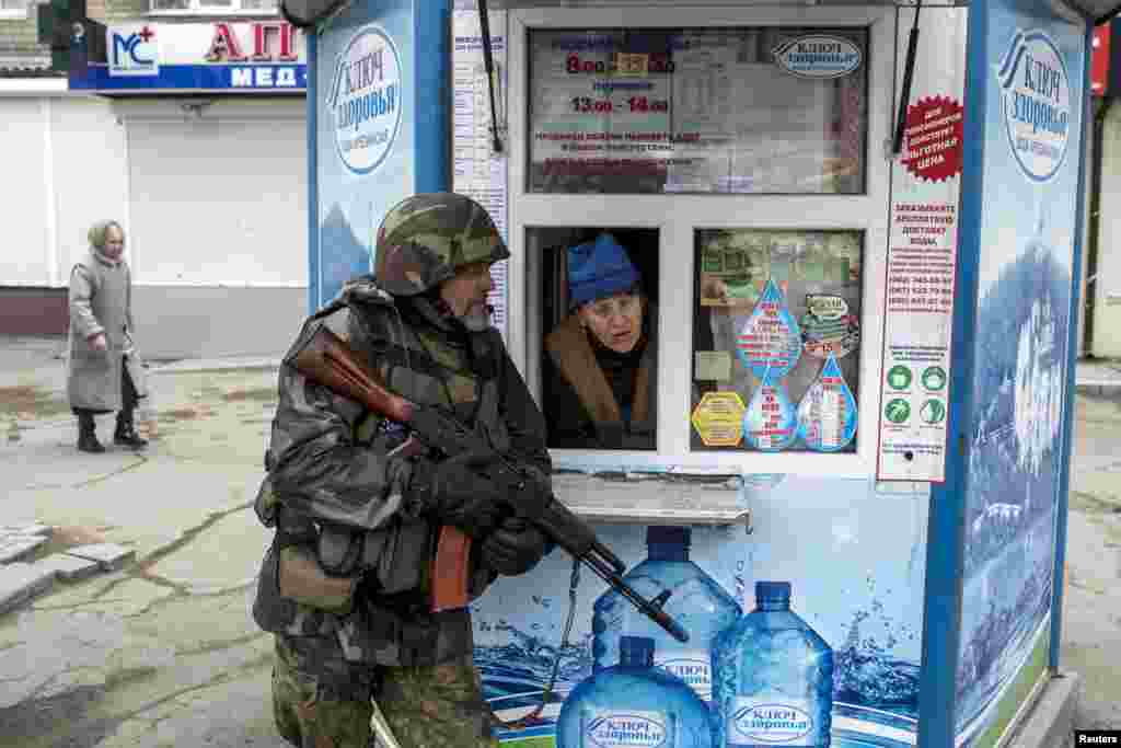 A pro-Russian rebel takes cover as a woman from inside a kiosk looks on, during what the rebels said was an anti-terrorist drill in Donetsk, Ukraine.