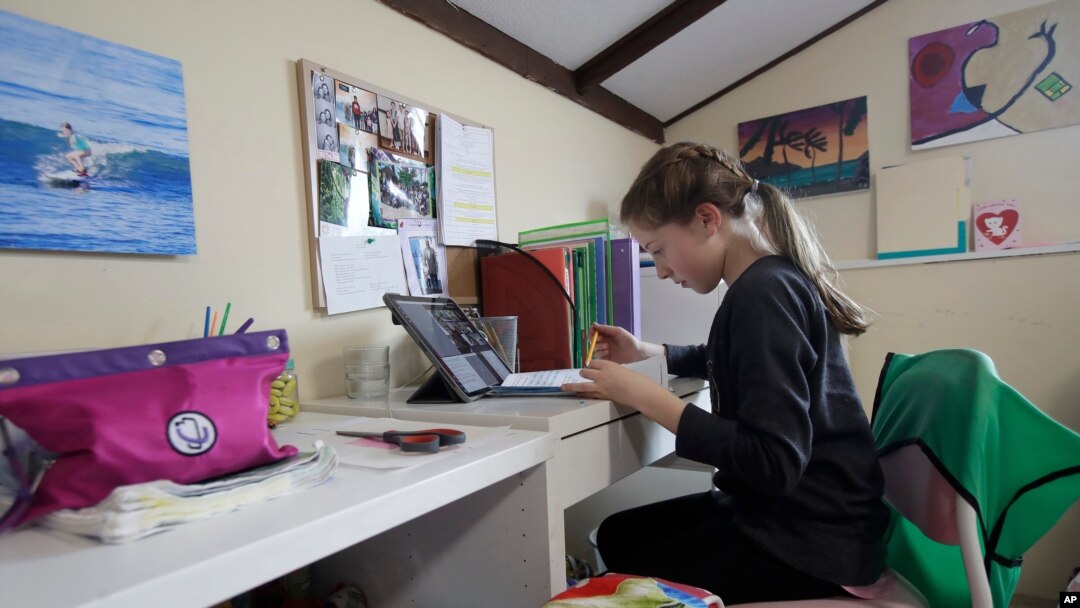 FILE - A student takes a class online at her home in San Francisco, March 19, 2020. Hundreds of students in Sioux Falls, South Dakota, did not take part in online learning when schools closed, one report shows.