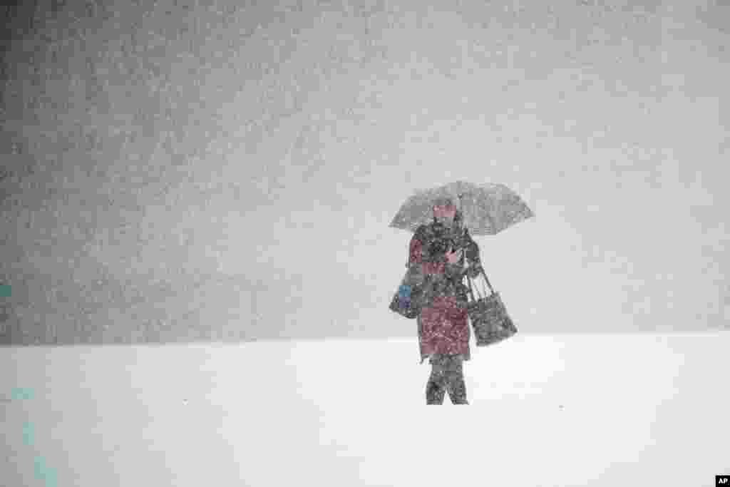 A person walks across Independence Mall during a snow storm in Philadelphia, Pennsylvania.