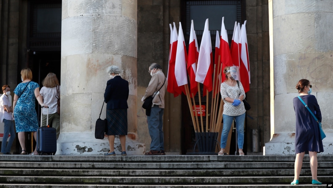 People keeping social distancing wait in line to vote in the presidential election in Warsaw, Poland, June 28, 2020.