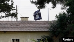 FILE - An Islamic State flag flies over the customs office of Syria's Jarablus border gate as seen from the Turkish town of Karkamis, in Gaziantep province, Turkey, Aug. 1, 2015. Three IS leaders were killed in a December 4 airstrike in Raqqa, IS' de facto capital in Syria, the Pentagon announced Tuesday.