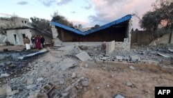 Libyans inspect a damaged building following a reported airstrike in the capital Tripoli's suburb of Tajoura, Dec.29, 2019.