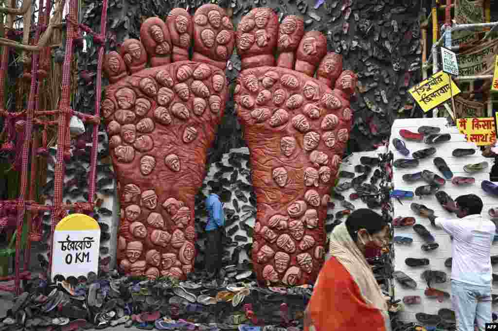 A person walk past workers decorating of a makeshift place of worship for Durga Puja with a theme in support the ongoing farmers protest against the central government&#39;s agricultural reforms, in Kolkata, India.
