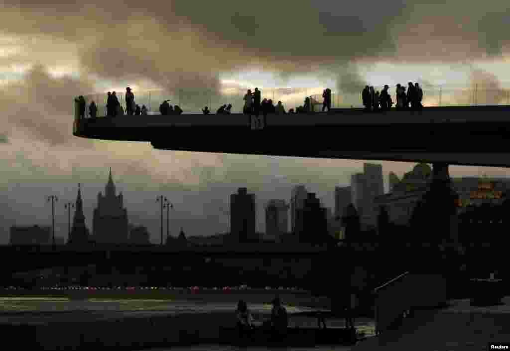 People gather on a pedestrian bridge over the Moskva River at Zaryadye Park, after new measures were imposed by local authorities to curb the spread of the COVID-19, in Moscow, Russia.