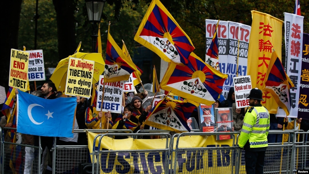 FILE - A man waves a Uyghur flag amongst pro-Tibet supporters as they demonstrate against China's President Xi Jinping outside Downing Street in central London, Britain, Oct. 21, 2015.