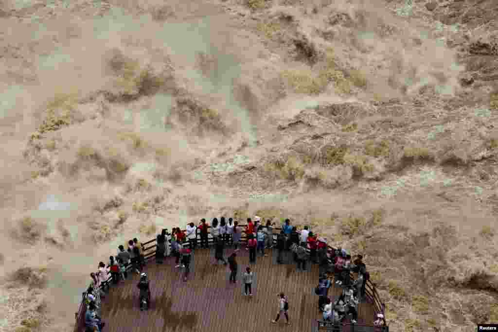 People watch the flooded Jinsha River from a sightseeing platform at Tiger Leaping Gorge, in Diqing, Yunnan Province, China.