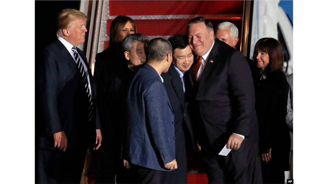 President Donald Trump, left, with first lady Melania Trump, watch Secretary of State Mike Pompeo, right, embrace former North Korean detainee Tony Kim, with Kim Hak Song, third from left, and Kim Dong Chul, front, upon their arrival, May 10, 2018, at Andrews Air Force Base, Md.