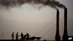 At a brick kiln, workers greet each other while preparing the kilns to fire bricks early morning on the main highway leading to Bagram, on the outskirts of Kabul, Afghanistan, Saturday, Oct. 26, 2013.