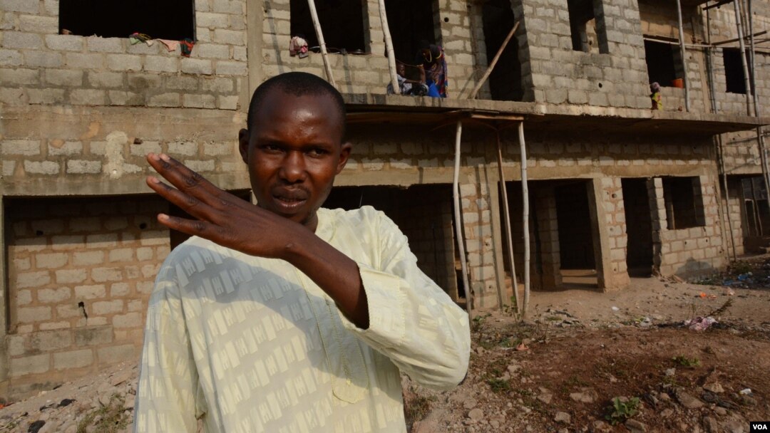 Prince Bala outside the half-finished construction where the IDPs are lodging. (VOA / K. Hoije)