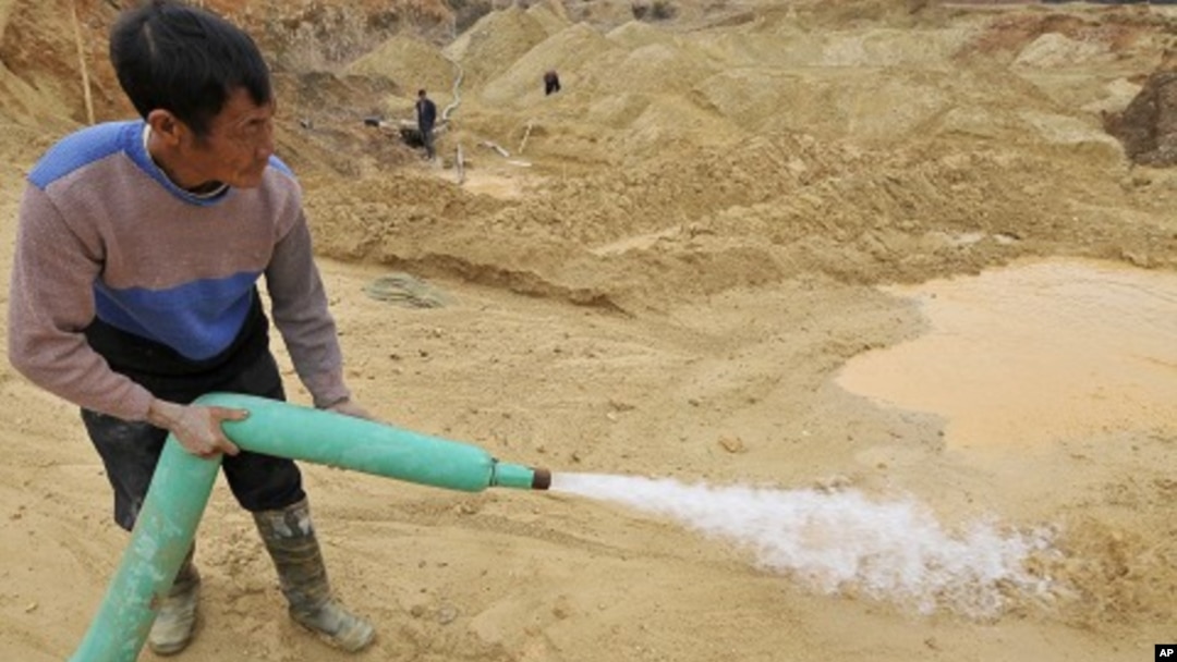 A worker waters the site of a rare earth metals mine at Nancheng county, Jiangxi province December 29, 2010.