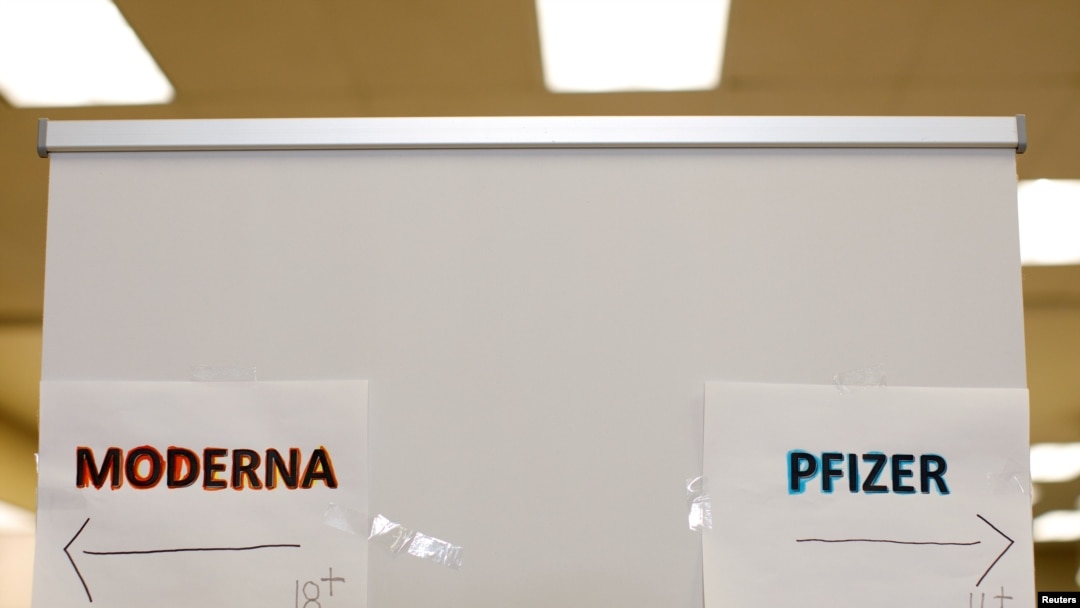 FILE - Signs and age groups are shown for the Pfizer and Moderna vaccines at a vaccination center in Chula Vista, California, Apr. 15, 2021.