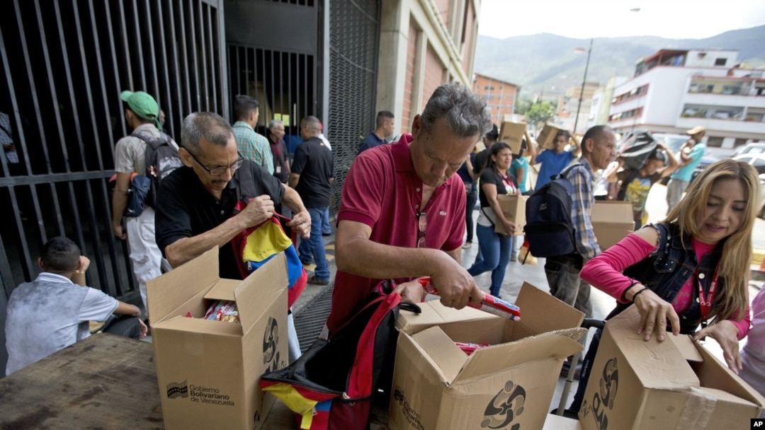 En esta imagen del 6 de julio de 2018, empleados de un centro cultural gestionado por el gobierno reciben las cajas con alimentos subsidiados distribuidas bajo el programa gubernamental "CLAP" , en el centro de Caracas, Venezuela. (AP Foto/Fernando Llano, Archivo)