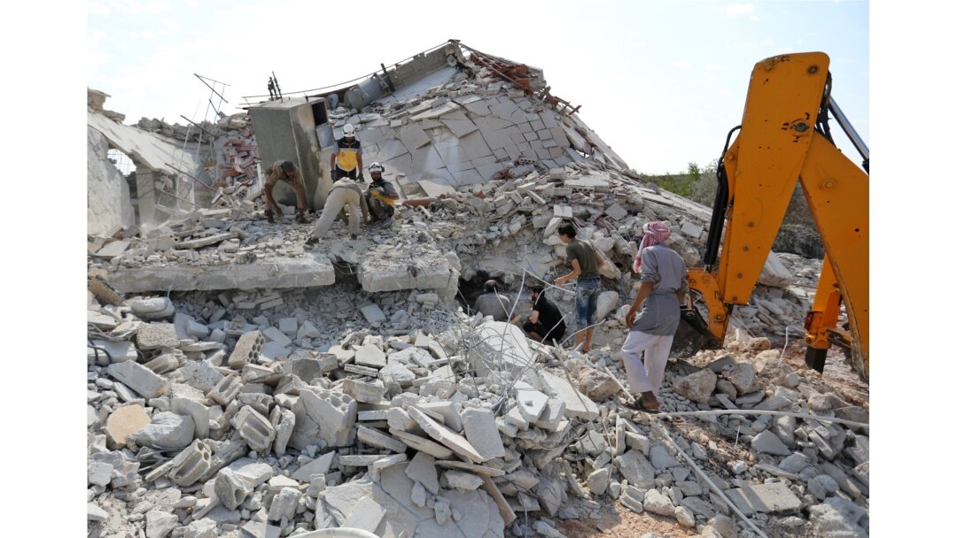 Members of the Syrian Civil Defense (White Helmets) search for victims amidst the rubble of a building that collapsed during reported airstrikes by pro-regime forces in the village of Beinin in the northern Idlib province, Aug. 20, 2019.