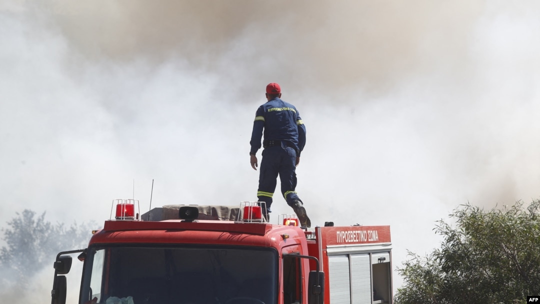 A firefighter looks at smoke from the roof of a fire vehicle after a wildfire broke out in Kitsi, a southern suburb of Athens on June 19, 2024.