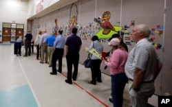 FILE - People line up to vote inside a precinct in Matthews, North Carolina, March 15, 2016.